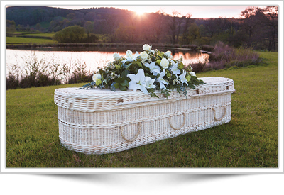 white woven funeral casket with sunset